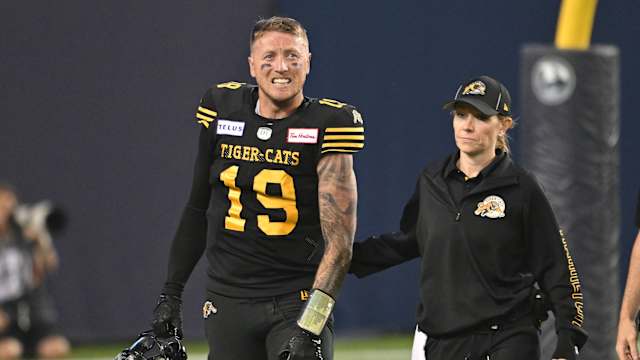 Jun 18, 2023; Toronto, Ontario, CAN; Hamilton Tiger-Cats quarterback Bo Levi Mitchell (19) is escorted off the field by team head therapist Claire Tofflemire after suffering an injury against the Toronto Argonauts in the fourth quarter at BMO Field. Mandatory Credit: Dan Hamilton-USA TODAY Sports